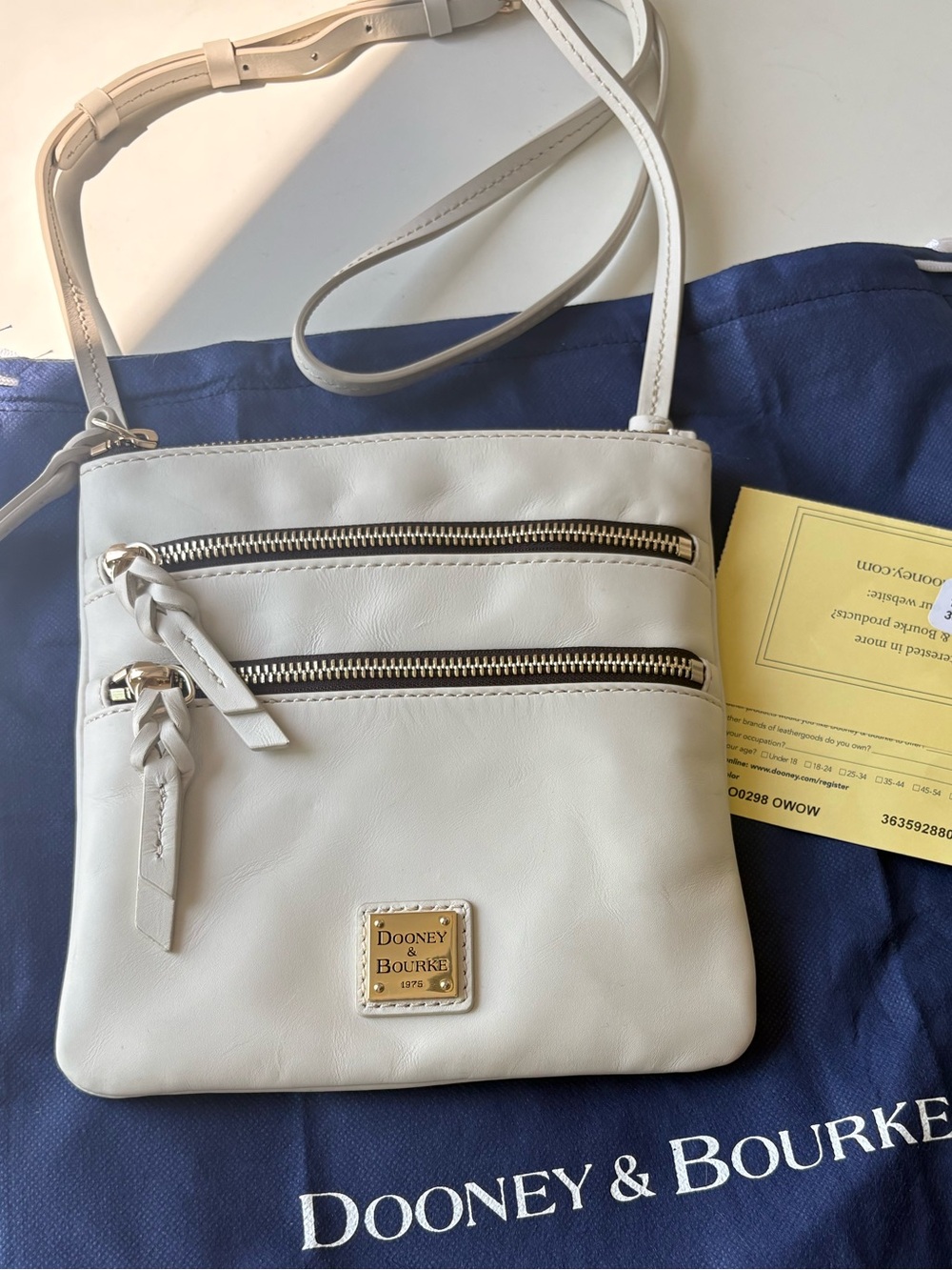 Dooney & Bourke Apollo Leather Triple Zip Crossbody bag in the color Off White